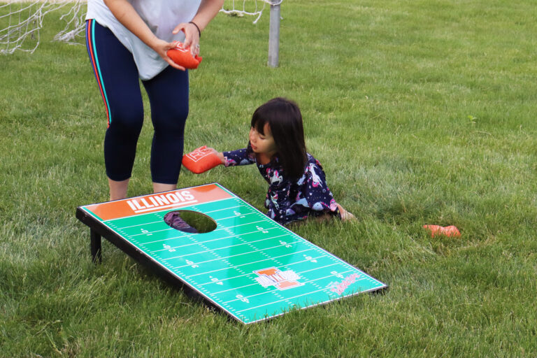 little girl puts beanbag into cornhole game