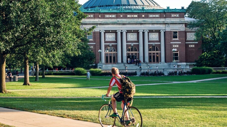 Man biking on quad in front of Foellinger Auditorium at UIUC